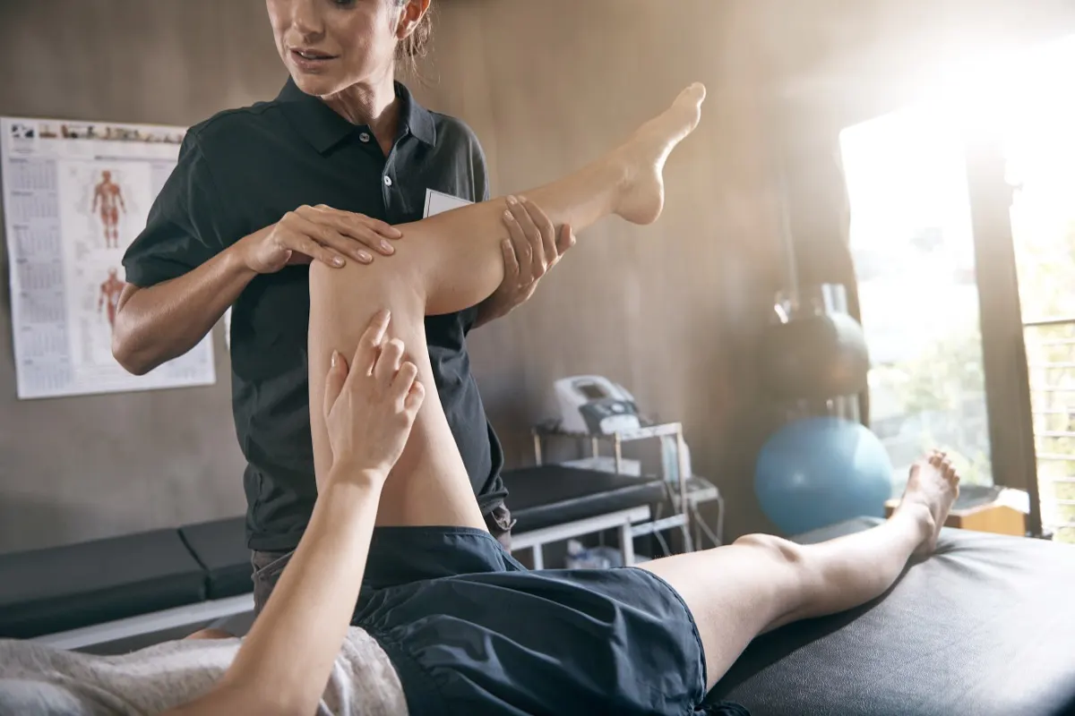 Physical therapist guiding a patient's leg through a stretch